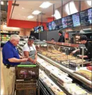  ??  ?? Market 32 customer Bob Leonard, in blue shirt, consults one of the store’s many helpful employees on the items available in the new FoodFare section