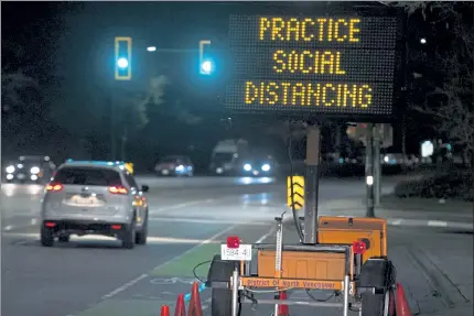  ?? AP ?? A highway sign reminds motorists in North Vancouver, British Columbia, about ‘social distancing’ to limit the spread of the coronaviru­s.