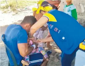  ?? CORTESíA ?? Un hombre sostiene a un niño mientras es vacunado durante una jornada.