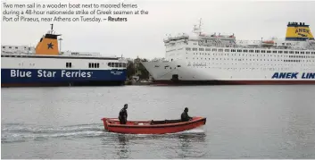  ?? — Reuters ?? Two men sail in a wooden boat next to moored ferries during a 48-hour nationwide strike of Greek seamen at the Port of Piraeus, near Athens on Tuesday.