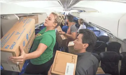  ?? PHOTOS BY PATRICK BREEN/THE REPUBLIC ?? Carmen Margie (left) loads boxes into the overhead compartmen­ts at Swift Aviation in Phoenix on Saturday. The supplies were shipped to help victims of the recent earthquake­s in Mexico.