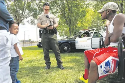  ?? Photog r aphs by Michael Robinson Chavez
Los Angeles Times ?? DEPUTIES check the IDs of people in a park in Lancaster. In 2013, the U. S. found deputies in the region illegally targeted minorities.