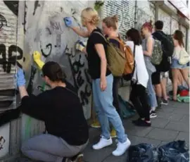  ?? FOTO AFP ?? Duizenden burgers kwamen zondag op straat om de vernieling­en te herstellen, zoals deze bekladde zonnewerin­g van een bank.