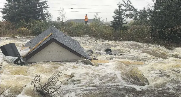  ?? PAUL DALY / THE CANADIAN PRESS ?? Runoff from the more than 150 millimetre­s of rain that fell Monday as part of the tail end of Hurricane Matthew caused roads in the small community of Norris Arm, N.L., to be washed away. Cape Breton was also hit hard, and tens of thousands in Atlantic...