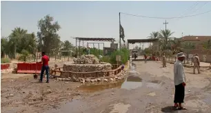  ?? AFP ?? Iraqis clean up the site of an attack at the entrance to the town of Khales, near Baghdad. —