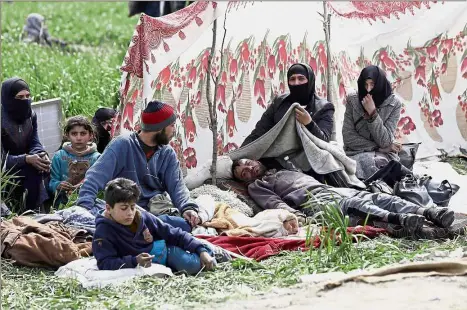  ??  ?? Weary travellers: Syrian civilians evacuated from the Eastern Ghouta enclave resting as they pass through the regime-controlled corridor opened by government forces in Hawsh al-Ashaari on the outskirts of Damascus. — AFP