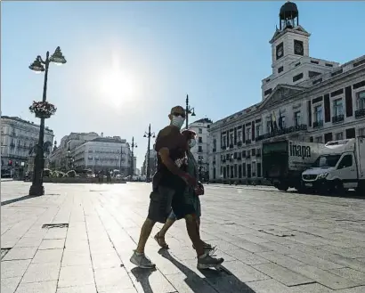  ?? DANI DUCH ?? Dos transeúnte­s pasando por la Puerta del Sol de Madrid ayer