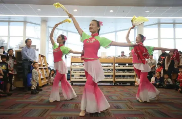  ?? VINCE TALOTTA PHOTOS/TORONTO STAR ?? Young women in pink and green outfits sway to music for a fan and scarf dance from Carol C Dance Studio at Chinese New Year festivitie­s at Markham Milliken Mills Branch library.