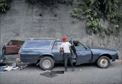  ?? / GABY ORAA ?? Un hombre limpiaba una camioneta convertida en furgón fúnebre en Caracas, el día 3.