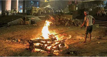  ??  ?? Tending to the dead: A Dom stoking a funeral pyre at the Manikarnik­a ghat. — AFP