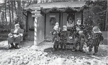  ?? LARS HAGBERG/GETTY-AFP ?? Christmas photos in the age of coronaviru­s: A family wears Christmas outfits as they pose Saturday for a photograph with Santa with Plexiglas in between to keep safe from COVID-19 in Kingston, Ontario, Canada. The province added another 1,822 cases of COVID-19 to its total on Saturday amid a troubling rise in infections across Canada.