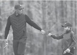  ?? PHELAN M. EBENHACK/AP ?? Tiger Woods gives his son Charlie a fist bump after Charlie made a putt during a practice round ahead of the PNC Championsh­ip onThursday.