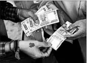  ?? AJIT SOLANKI/AP 2016 ?? Men exchange rupees in India right before the country banned its high-denominati­on currency in 2016.