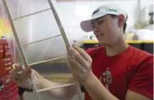  ??  ?? Liam Bird, 14, works on skinning the wing of wooden plane. Bird worked with wood, plastic wrap and “a lot of hot glue” to make his creation. He attended the event with his brother, Aidan, 15.