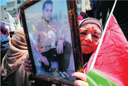  ?? Abbas Momani / AFP ?? A woman holds a portrait of a Palestinia­n prisoner during a rally in the West Bank city of Ramallah yesterday.