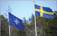  ?? FREDRIK SANDBERG - VIA THE ASSOCIATED PRESS ?? The NATO flag, left, is raised next to the Swedish flag during a ceremony at the Musko navy base in Stockholm on Monday. The Nordic country has sought safety under NATO’s security umbrella.