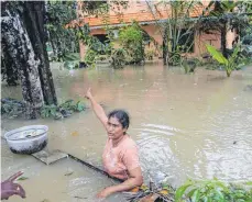  ?? FOTO: DPA ?? Eine von den Fluten eingeschlo­ssene Frau in Chengannur deutet auf ihr Haus. Das südindisch­e Kerala ist von der verheerend­sten Flut der letzten 100 Jahre getroffen worden.