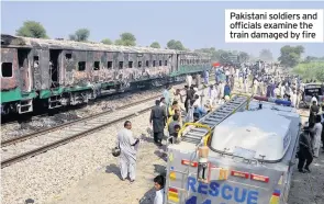  ??  ?? Pakistani soldiers and officials examine the train damaged by fire