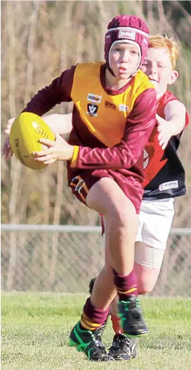  ??  ?? Drouin Maroon’s Kyle Hanks tries to outrun Koo Wee Rup chaser Charlie Perry in the under 10s game on Saturday morning.