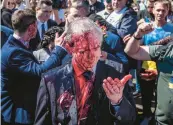  ?? WOJTEK RADWANSKI/GETY-AFP ?? Protesters opposed to the war in Ukraine douse Ambassador Sergey Andreev with red paint Monday at the Soviet Military Cemetery in Warsaw, Poland.