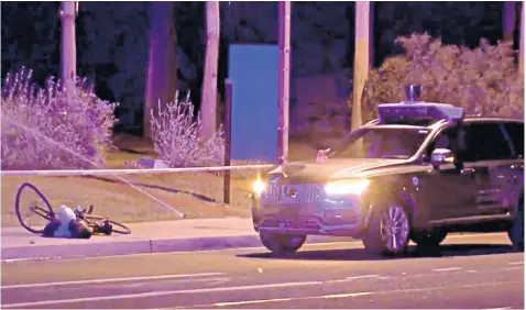  ??  ?? A bicycle and bags – it is not known whether they were the victim’s – lie near the Uber vehicle that crashed into the woman in Tempe, Arizona