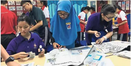  ??  ?? Students work through a newspaper activity during a workshop conducted by Shyamala in SMK Taman Tun Aminah, Skudai, Johor.