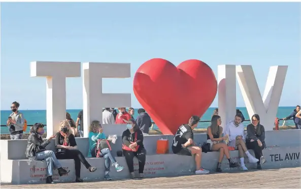  ?? FOTO: GIDEON MARKOWICZ/DPA ?? Menschen sonnen sich in Tel Aviv auf einer Promenade an der Küste des Mittelmeer­es.