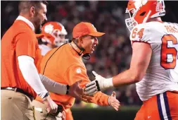  ?? AP Photo/Sean Rayford ?? ■ Clemson head coach Dabo Swinney congratula­tes players Nov. 27 after a score during the first half of the team’s NCAA college football game against South Carolina on in Columbia, S.C.