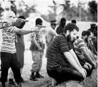  ??  ?? An ISIS video shows masked gunmen about to execute captured Syrian troops, who were
forced to dig their own graves.