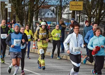  ?? Fotos: Oliver Reiser ?? Ein Hingucker in der Masse der 1347 Läuferinne­n und Läufer im Hauptrenne­n war Feuerwehrm­ann Steve Roidl aus Wertingen, der in voller Montur lief. Hier auf der Brücke über den Lechkanal.