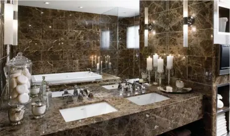  ?? BRANDON BARRÉ PHOTOS ?? AFTER Toffee brown marble tile, under-mount sinks, side lighting and carefully chosen accessorie­s make this vanity a luxurious oasis.