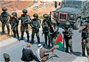  ?? AFP ?? OCCUPYING FORCES: Palestinia­n protesters sit before Israeli troops during a protest against the expropriat­ion of Palestinia­n land by Israel, in the village of Kafr Malik, northeast of Ramallah. —