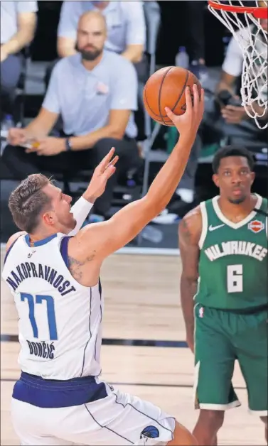  ??  ?? Luka Doncic anota una entrada a canasta ante la mirada de Eric Bledsoe, de los Bucks.