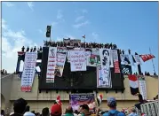  ?? HADI MIZBAN — THE ASSOCIATED PRESS ?? Iraqi anti-government protesters hang their demands and slogans on Wednesday while standing on a building near Tahrir Square in Baghdad.