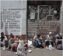  ??  ?? Migrantes venezolano­s descansan mientras reciben comida, delante de un muro con pasajes de la Biblia, en Pamplona, Colombia