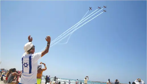  ?? (Reuters) ?? BEACHGOERS WATCH the Israeli Air Force Aerobatic Team fly over the Mediterran­ean Sea during celebratio­ns of Independen­ce Day.