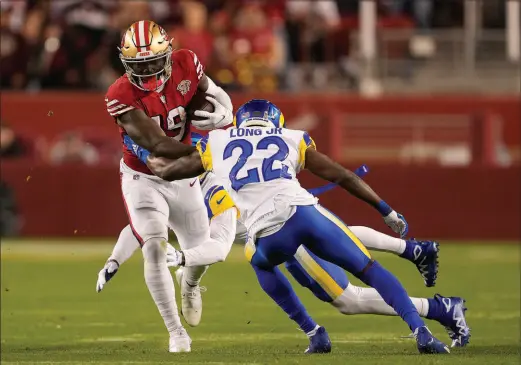  ?? TONY AVELAR / ASSOCIATED PRESS ?? San Francisco 49ers wide receiver Deebo Samuel (19) tries to run through a tackle by Los Angeles Rams defensive back David Long Jr. (22) and cornerback Jalen Ramsey on Sunday in Santa Clara, Calif. Samuel scored two touchdowns in a 31-10 win.