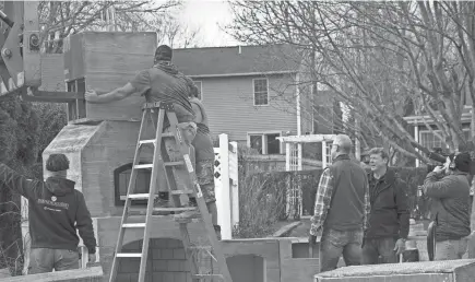  ?? SUBMITTED ?? Kevin O’connor, second to left, and Scott Widmer, third to left, watch as Round Grove Products employees install the top of the outdoor fireplace.