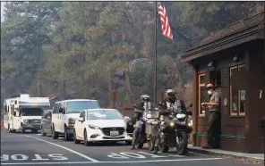  ?? AP/GARY KAZANJIAN ?? Park Ranger Alex Martinez wears a mask Tuesday as he passes out maps and directions to visitors at the California Highway 140 gate as Yosemite National Park reopens after being closed because of wildfires.