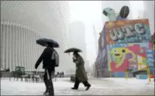  ?? JULIO CORTEZ — THE ASSOCIATED PRESS ?? Pedestrian­s hold umbrellas while walking under light snow in lower Manhattan, Wednesday, near The Oculus transporta­tion hub in New York.