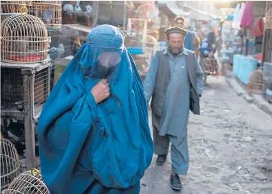  ?? HECTOR RETAMAL/GETTY-AFP ?? An Afghan burqa-clad woman walks in a market where birds are sold Oct. 31 in Kabul.