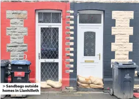  ??  ?? > Sandbags outside homes in Llanhillet­h