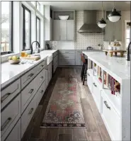  ?? GRACE LAIRD PHOTOGRAPH­Y/MOORE HOUSE INTERIORS VIA AP ?? This 2019 photo shows a kitchen designed by interior designer Ashely Moore. In this kitchen Moore used a vintage Moroccan rug which adds warmth and color, and its appealingl­y worn look blends beautifull­y with the reclaimed wood floor.