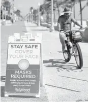  ?? MIKE STOCKER/SOUTH FLORIDA SUN SENTINEL ?? Signs along the beach in Hollywood remind people of the requiremen­t to wear masks unless exercising 6 feet away from others.