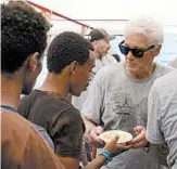  ?? FRANCISCO GENTICO/AP ?? Actor Richard Gere, right, helps serve meals to migrants aboard the Open Arms humanitari­an ship.