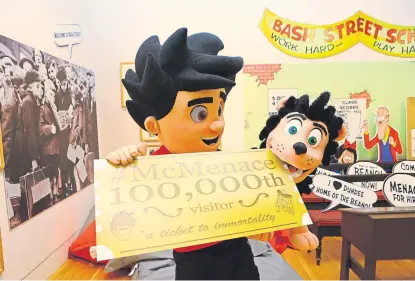  ?? Pictures: Dougie Nicolson. ?? Gnasher gets his teeth into the Golden Ticket for the 100,000th visitor at the McMenace Galleries in Dundee.