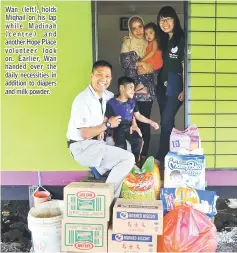  ??  ?? Wan (left), holds Miqhail on his lap while Madinah (centre) and another Hope Place volunteer look on. Earlier, Wan handed over the daily necessitie­s in addition to diapers and milk powder.