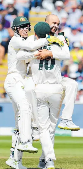  ?? Photo / AP ?? Wizard of Oz Nathan Lyon is embraced by captain and wicketkeep­er Tim Paine (left) and Peter Siddle after grabbing the wicket of Joe Root.