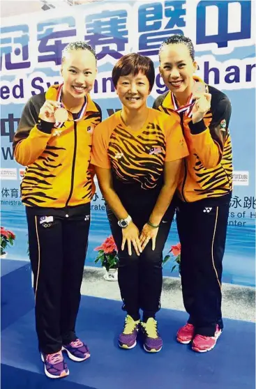  ??  ?? Good showing: Gan Hua Wei (left) and partner Zylane Lee Yhing Huey standing either side of coach Long Yan for a photograph after winning the bronze in synchronis­ed swimming at the China Open in April.