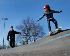  ??  ?? PERFECT BALANCE: Sofia Clark, 7, of Cambridge, skates down a slope while getting some tips from her dad, Ben, Sunday at Smith Park.